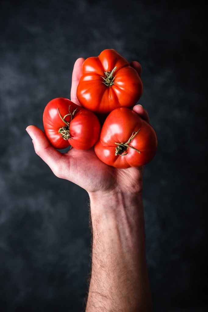 Hand holding fresh red tomatoes